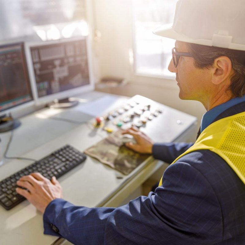 Male worker using computers at manufacturing plant
